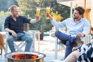 Two friends enjoying a drink around a smokeless firepit